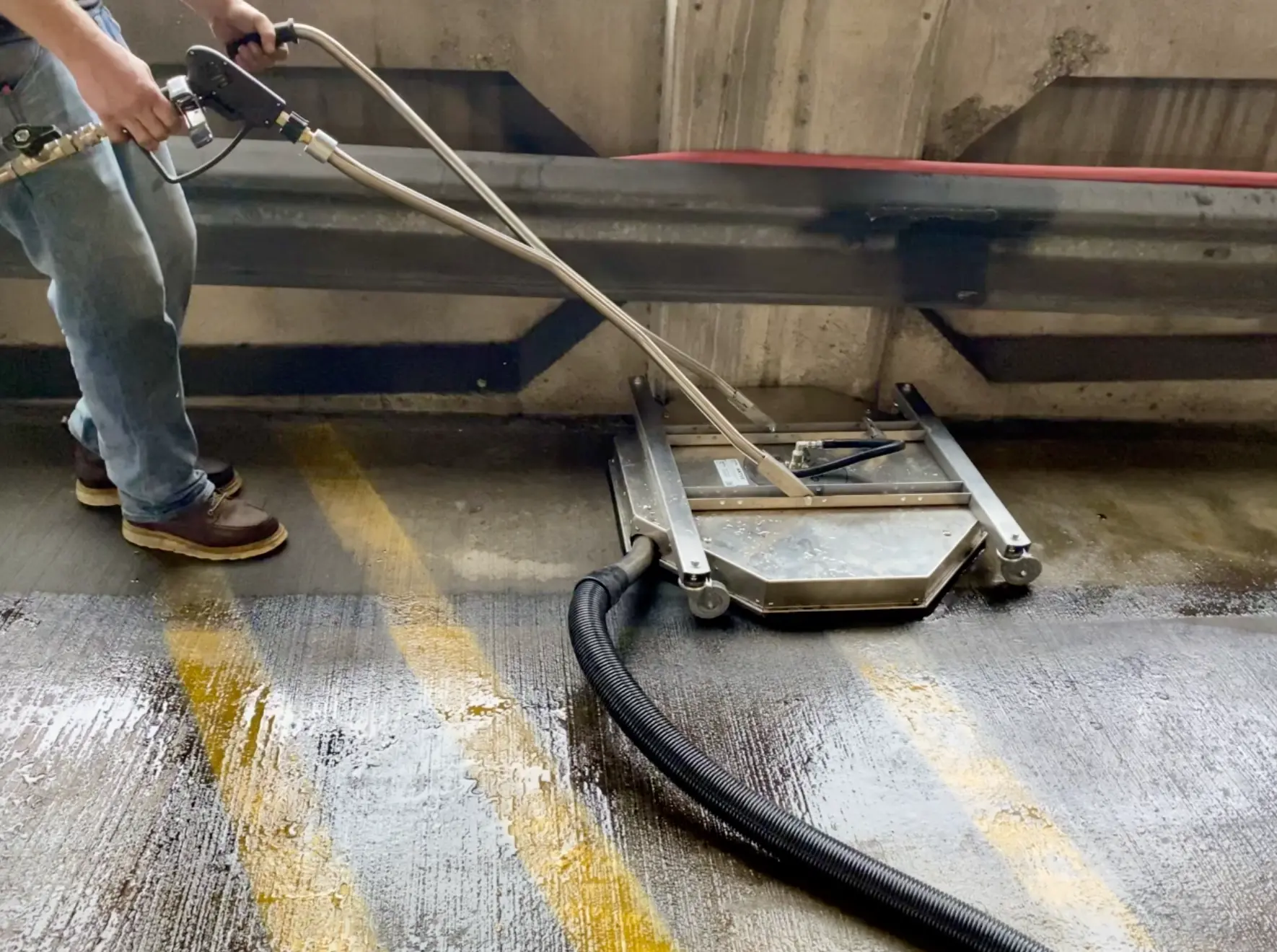 Vacuum water recovery pressure washing system in action inside a New Orleans parking garage